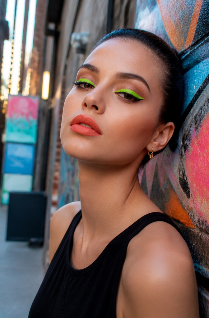 Make Up Inspo Pics: Looks, Techniques & Color Guides for 2026 3 A model with neon makeup featuring green eyeliner and coral lips in an urban setting.