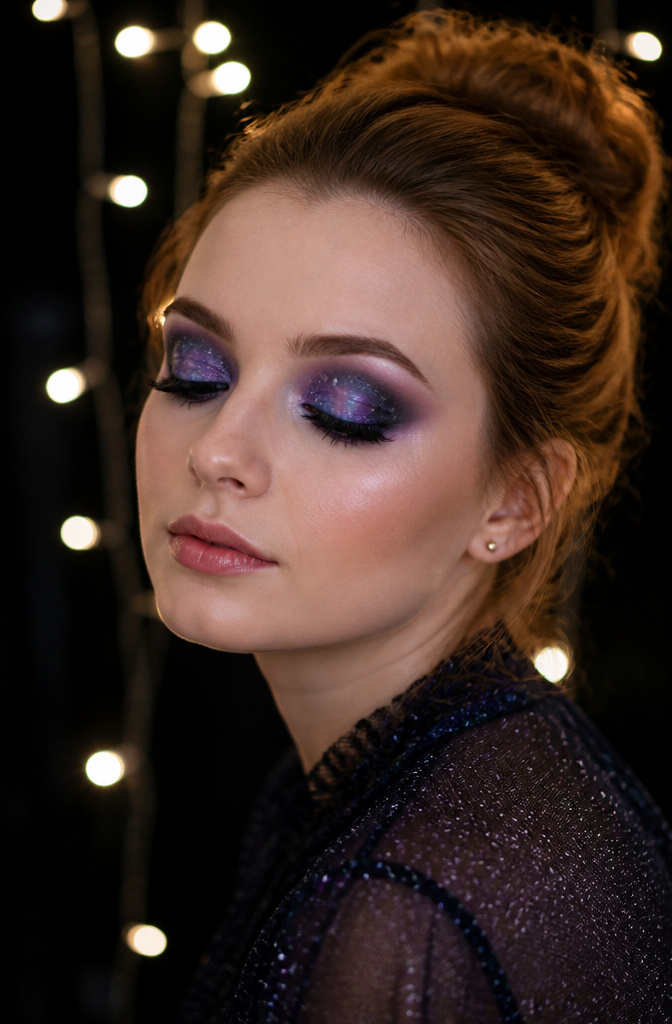 Model showcasing galaxy-inspired eye makeup with stars and dark hues.