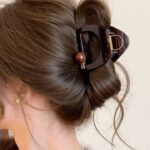 Brown hair styled in a bun secured with a dark brown claw clip.