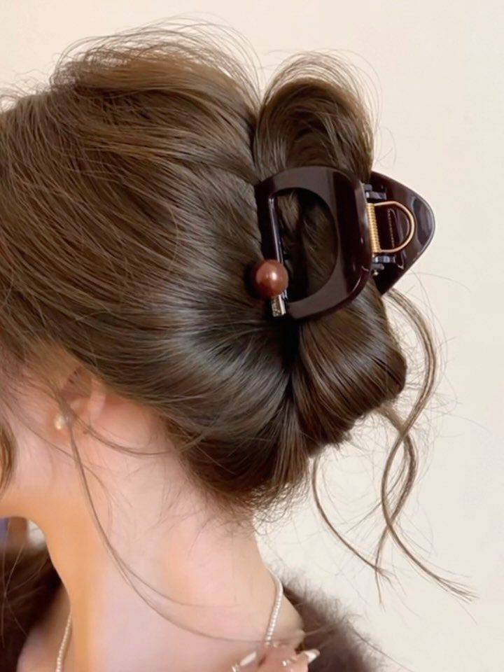 Brown hair styled in a bun secured with a dark brown claw clip.