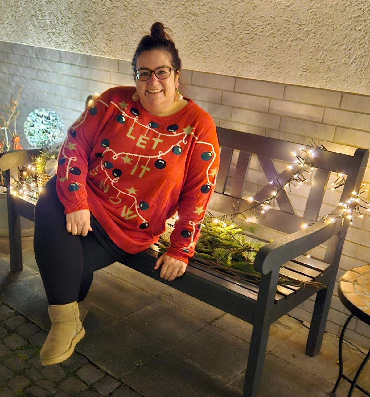 Woman wearing a red ugly Christmas sweater with a garland and stars design.