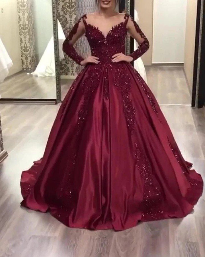 Burgundy satin ball gown with long sleeves and beaded embroidery on a person.